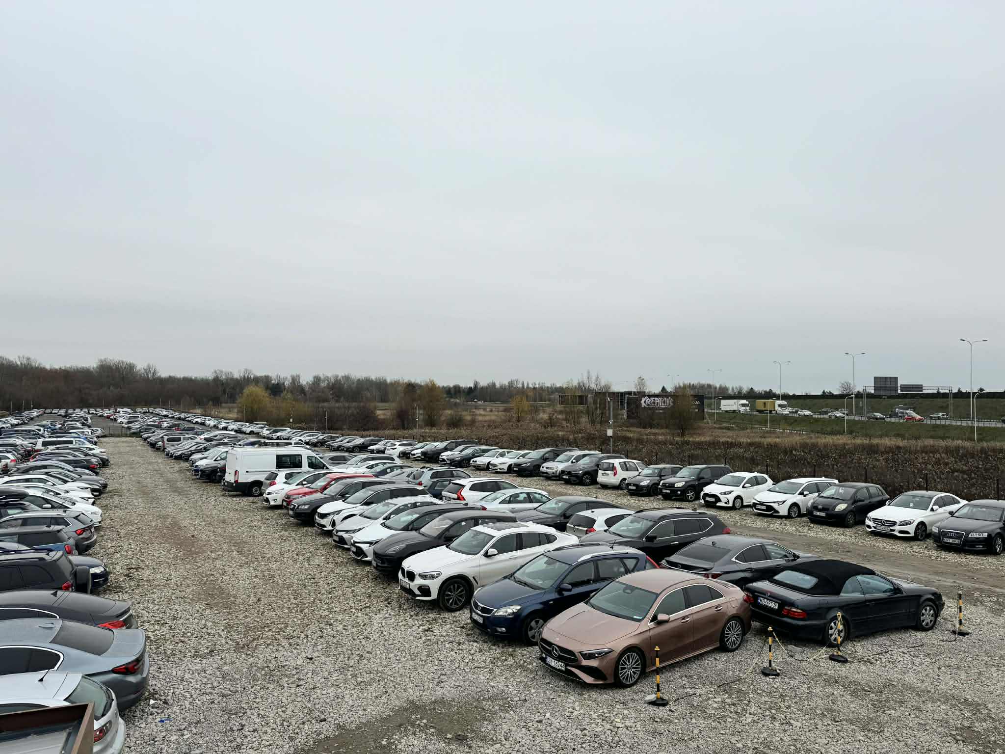 Profesjonalnie oznakowany i ogrodzony plac postojowy Skyway Parking blisko lotniska Chopina – bezpieczne miejsca parkingowe z darmowym transferem i monitoringiem 24/7 na Okęciu.